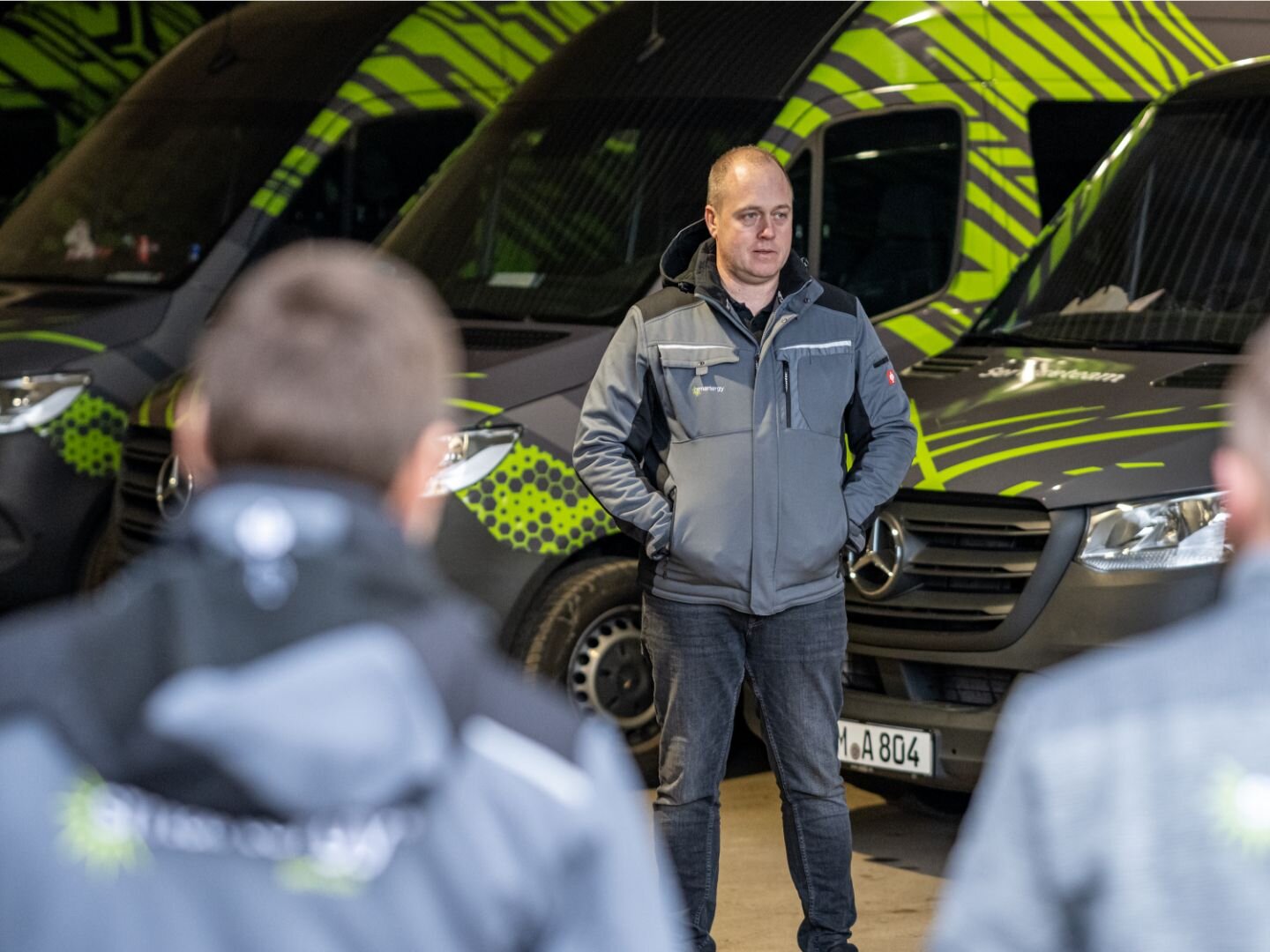 Teambesprechung mit Firmenfahrzeugen im Hintergrund